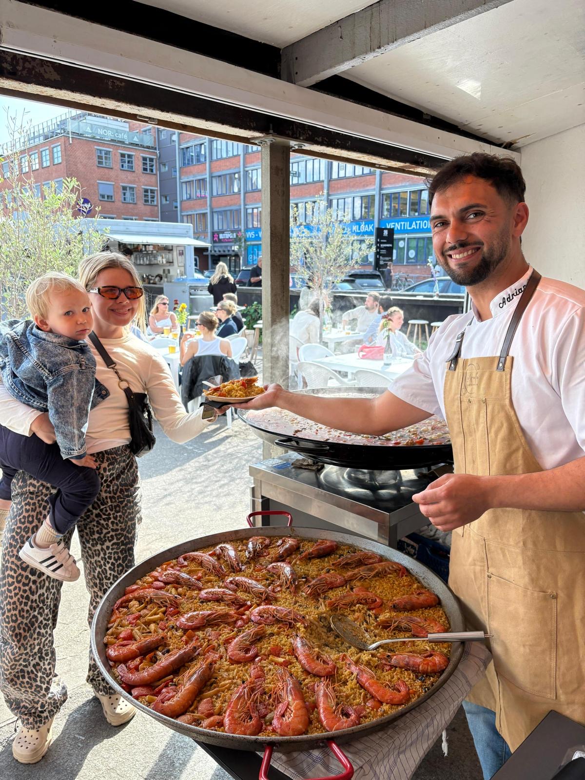 Adrián serving paella to a guest